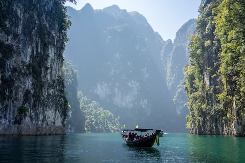A longtail boat drifting between limestone cliffs