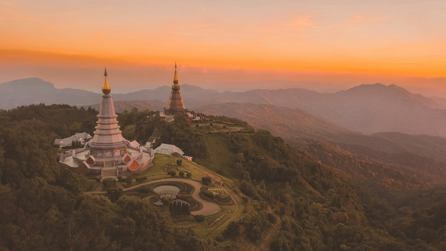 A golden pagoda on a hillside at sunset