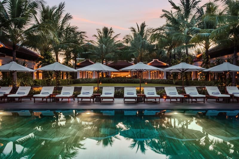 A resort pool lined with cabanas and palm trees